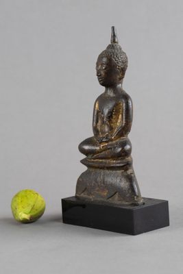 statue représentant une personne assise sur un rocher à côté d'une balle de tennis