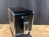 a black coffee machine sitting on top of a wooden table