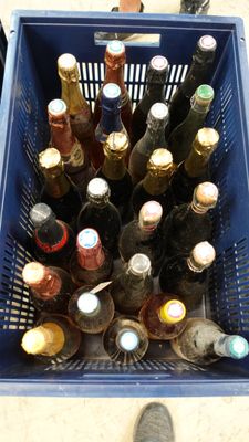 a blue basket full of bottles of beer on the floor