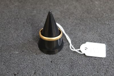 un cône noir surmonté d'un anneau doré
