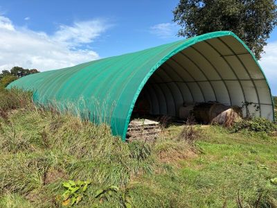 un grand abri vert situé au milieu d'un champ