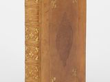 un vieux livre à la couverture dorée, ornée d'un motif raffiné sur la page de garde