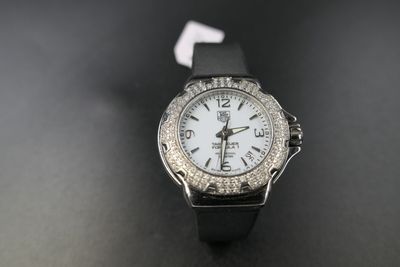 a close up of a watch with a white face on a black surface