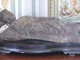 une statue représentant une femme allongée sur une table en bois