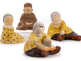 three figurines of people sitting on a white surface