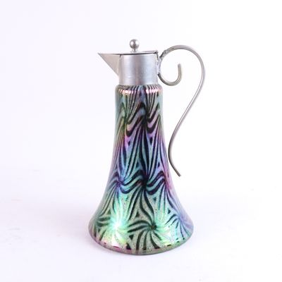 un pichet en verre coloré muni d'une poignée en métal, sur fond blanc