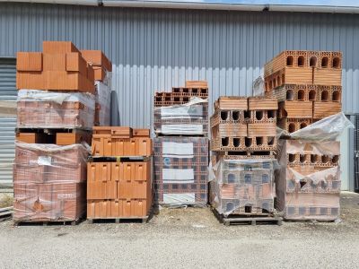de nombreuses piles de briques empilées sur des palettes devant un bâtiment