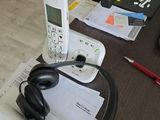 un téléphone portable et des écouteurs posés sur un bureau, à côté d'un ordinateur