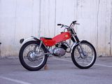 a red motorcycle parked in a parking lot next to a white wall