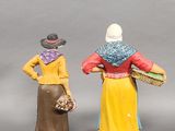 two figurines of a woman and a man standing next to each other