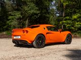an orange sports car parked in a gravel lot