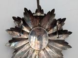 a silver flower shaped object hanging on a wall