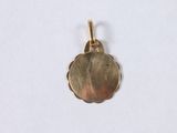 a close up of a gold plated pendant on a white surface