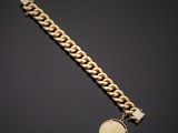a gold bracelet with a coin on a black background