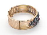 a close up of a gold bracelet on a white surface