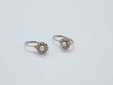 a pair of pearl and gold earrings on a white surface
