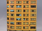 yellow building with a bird on top of it on a gray surface