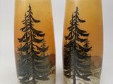 two tall vases with trees painted on them sitting on a table