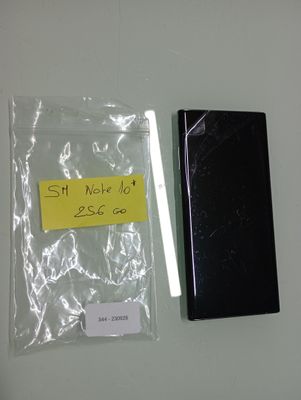 a black cell phone next to a yellow sticker on a white wall
