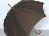 un parapluie marron avec un manche en bois sur une surface blanche