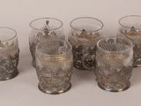 six glasses and a tray with silverware on a white surface