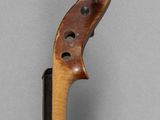 an old violin with a wooden bow on a gray surface