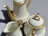 three pieces of white and gold tea and coffee set on a gray surface