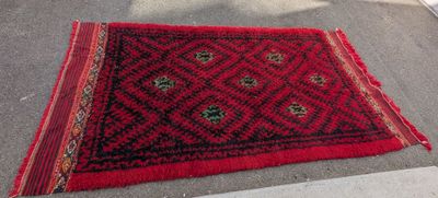 le tapis posé au sol est rouge et noir, avec un motif en losanges