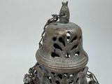 a metal bell with a bird on top of it