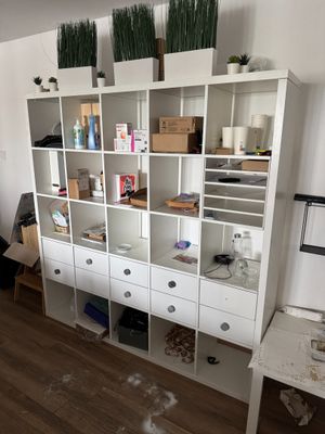a white bookcase with lots of drawers and plants on top of it