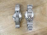 two watches sitting on a wooden table next to each other