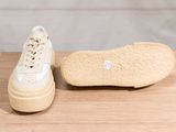 the sole of a pair of white sneakers sitting on top of a wooden table