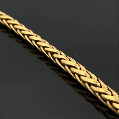 gros plan d'un bracelet en or sur une surface noire