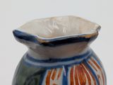 a blue and orange vase sitting on a white surface