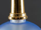 a blue bottle with a gold cap sitting on a table