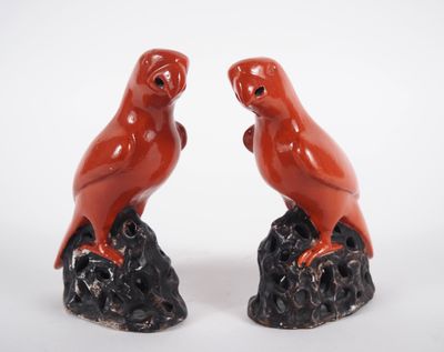 une paire d'oiseaux en céramique rouge posés sur un rocher, sur fond blanc