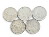 six types différents de pièces d'argent posées sur une surface blanche