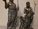 deux statues représentant un homme et une femme accompagnés d'un chien, posées sur une table