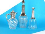 trois vases en verre et un vase en argent sur fond bleu