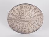 an old silver plate with writing on it on a white surface