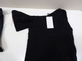 a black t - shirt on a white table next to a pair of jeans