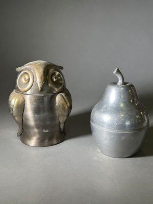 un vase en argent et une figurine de chouette posés l'un à côté de l'autre