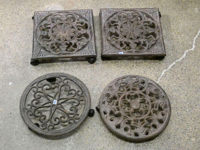 quatre grilles de cheminée anciennes en fonte posées sur un sol en béton