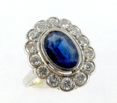 gros plan d'une bague avec une pierre bleue entourée de diamants