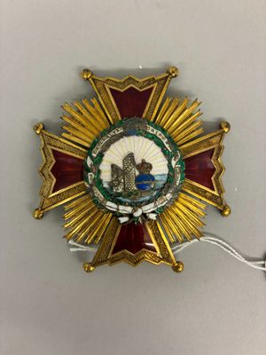 une image représentant un insigne doré et rouge sur lequel figure l'image d'un homme dans un bateau