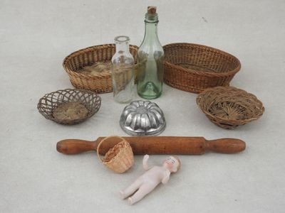une table sur laquelle sont posés un rouleau à pâtisserie en bois, une bouteille en verre, un rouleau à pâtisserie en bois, une cuillère en bois et d'autres objets