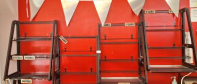 Plusieurs échelles sont alignées contre un mur rouge dans une pièce.