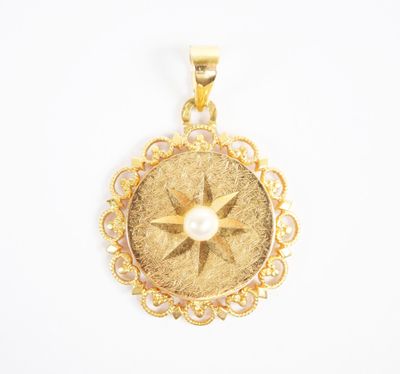 a close up of a gold pendant with a pearl in the center