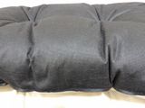 a close up of a black pillow on a white bed