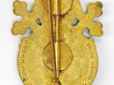 gold colored broochle with a metal pin on top of it
